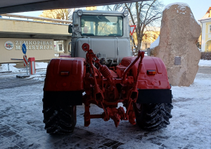 Sarkans traktors sniegotā pilsētvidē