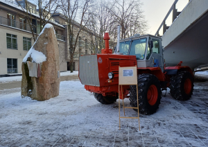 Sarkans traktors sniegotā pilsētvidē