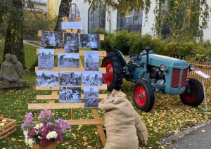 Lapkritis zem bērziem, kurā nolikts senlaicīgs traktors, brūni maisi un senlaicīgas fotogrāfijas