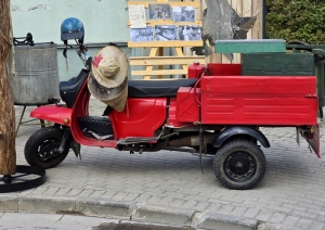 Sarkans motorollers ar kravas kasti pilsētvidē