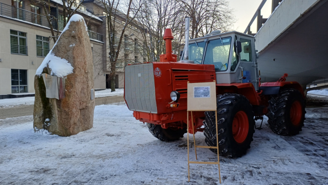 Sarkans traktors sniegotā pilsētvidē