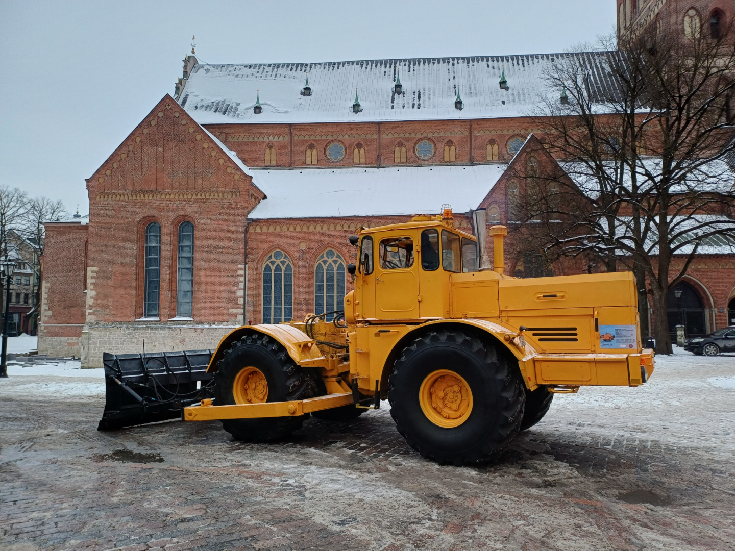 Dzeltens, senlaicīgs traktors sniegotā Doma laukumā