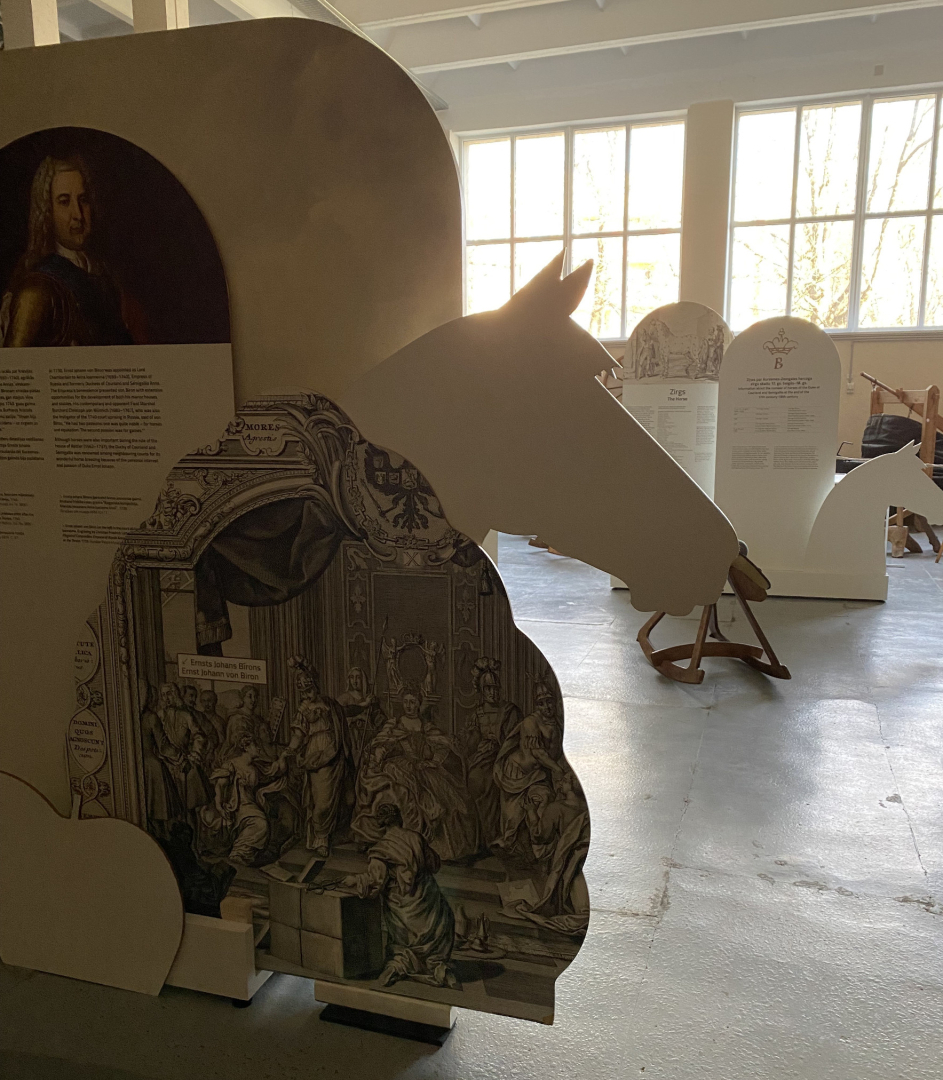 Liela, informatīva stenda sānu mala ar zirga galvu muzeja telpās par zirgu un zirgošanās tēmu