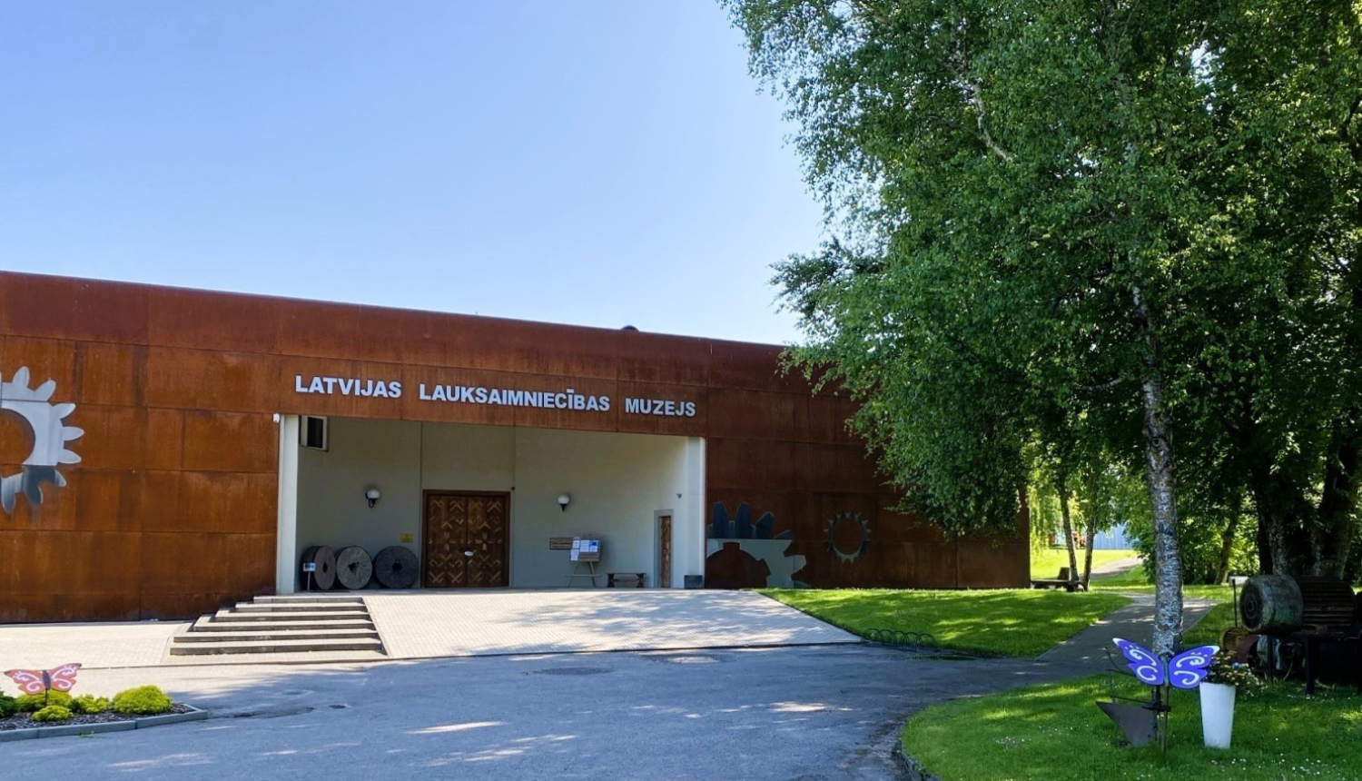 Ceļš uz Latvijas Lauksaimniecības muzeja galveno ieeju. Ceļa malā dekoratīvi tauriņi