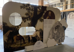 Liels, informatīvs stends muzeja telpās par zirgu un zirgošanās tēmu