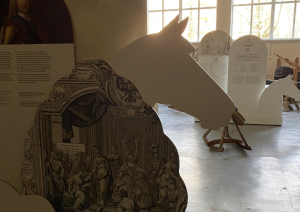 Liela, informatīva stenda sānu mala ar zirga galvu muzeja telpās par zirgu un zirgošanās tēmu